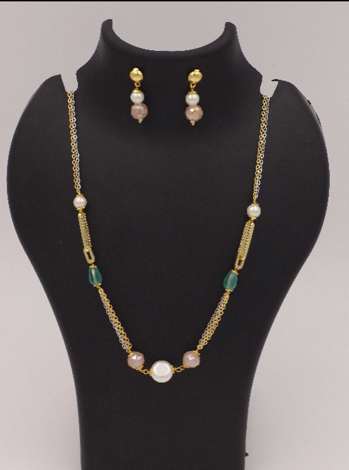 Gold-tone necklace and matching earrings set with pearls, green beads, and blush pink stones on black display stand.